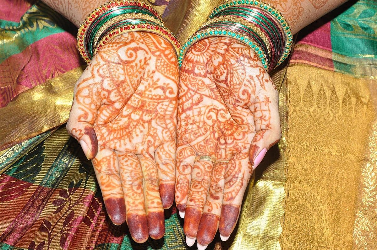 Illustrative photo: mehndi-decorated bridal hands on a yellow saree
